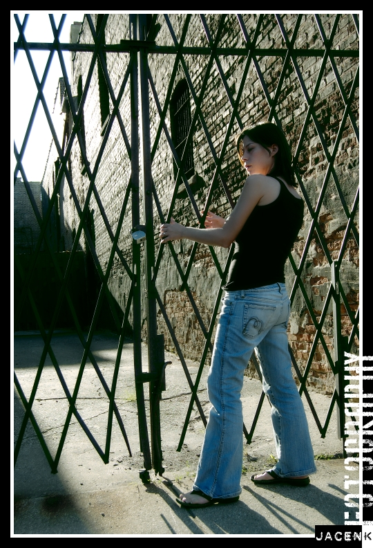 Fashion model poses by fence for Vogue Assassin shoot by photographer Jason Kraynek