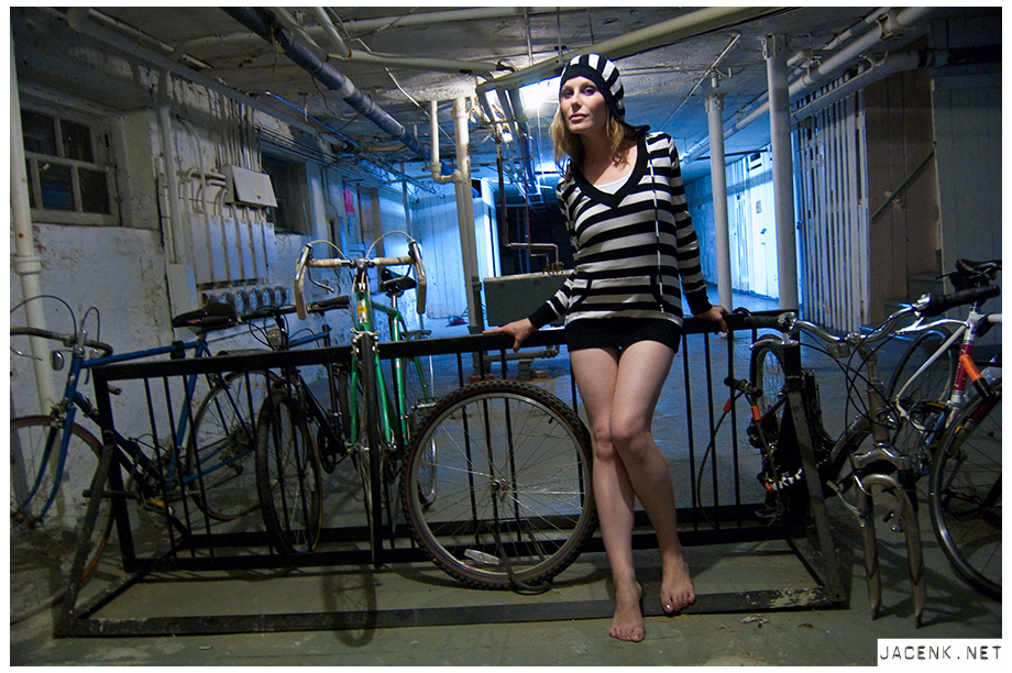model in basement next to bike rack with striped hooded shirt