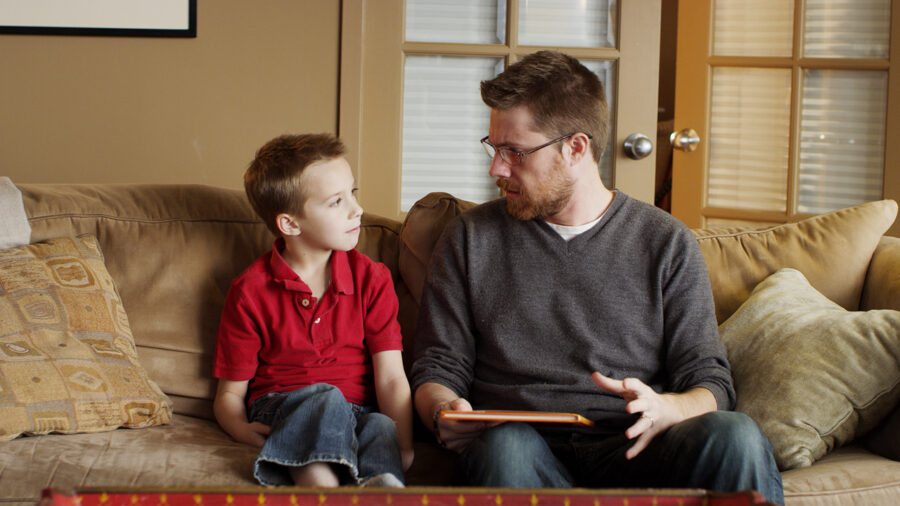 Father and son on a couch with a book.