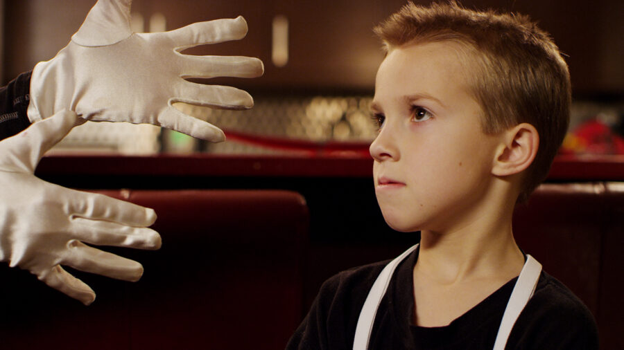 Kid in mime outfit looking at gloved hands.