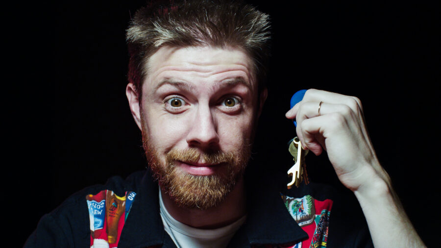 Man shows his keychain to the camera with a smile.