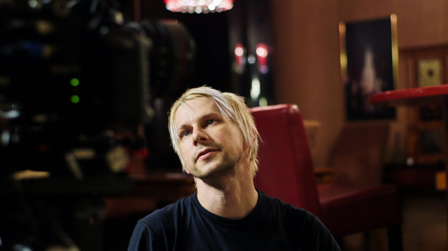 Man with bleached hair looking up in a dinning room.