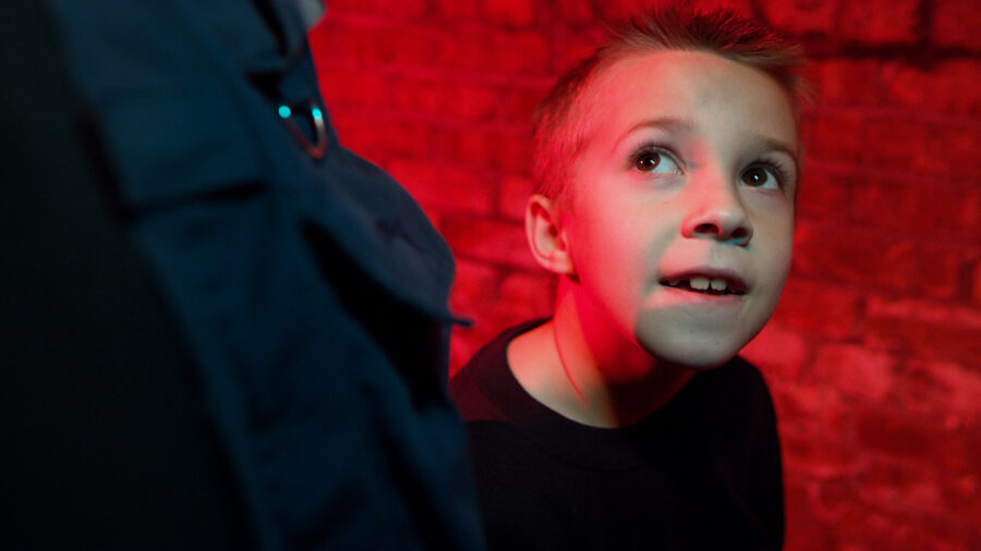 Young boy in a red room looks up at his father.