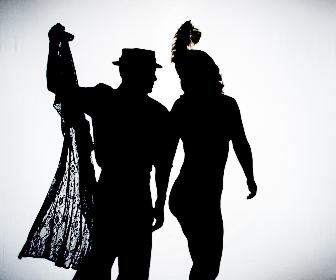 Shadow figures of a circus performance duo dancing and removing clothing.