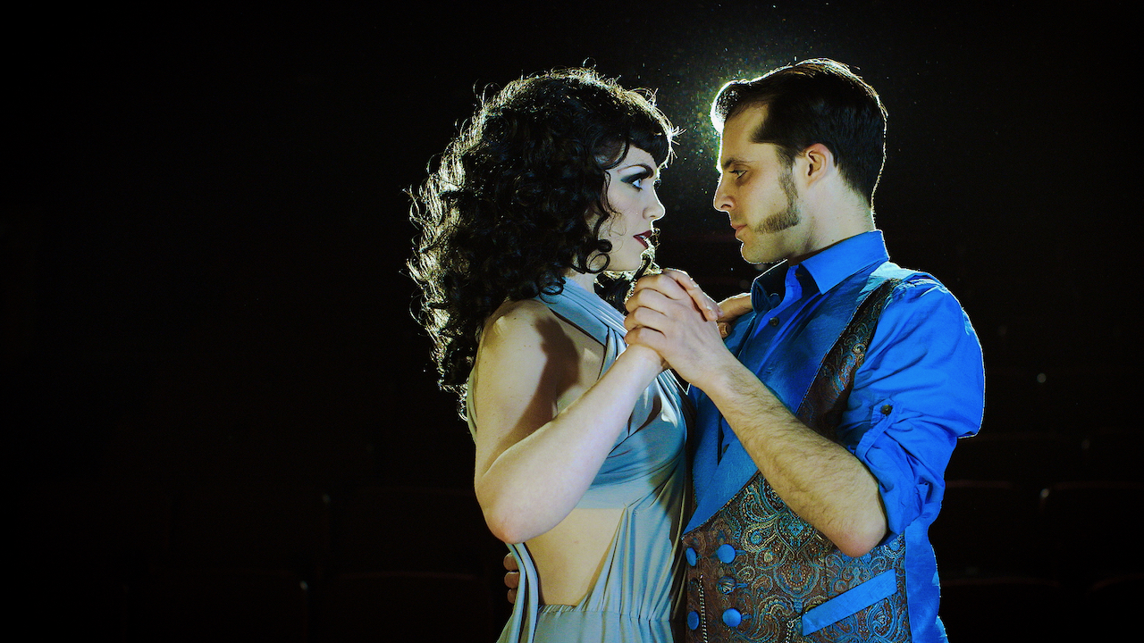 Man and woman dance in a blue light onstage.