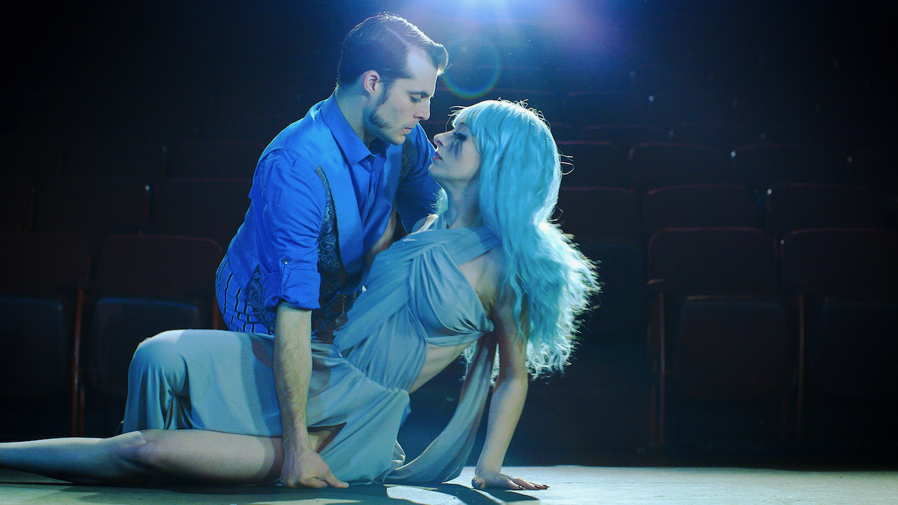 Man and woman dance in a blue light onstage.