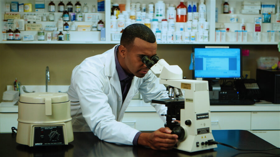 AVMA Life ad campaign actor looks through a microscope in a lab shot by cinematographer Jason Kraynek
