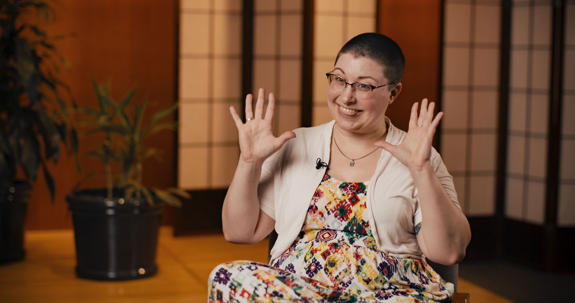 Woman with funny expression being interviewed in a warm colored room with wall blinds.