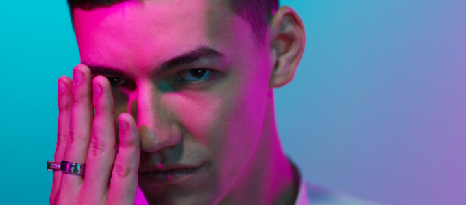 music artist in pink and blue lights with hand at face
