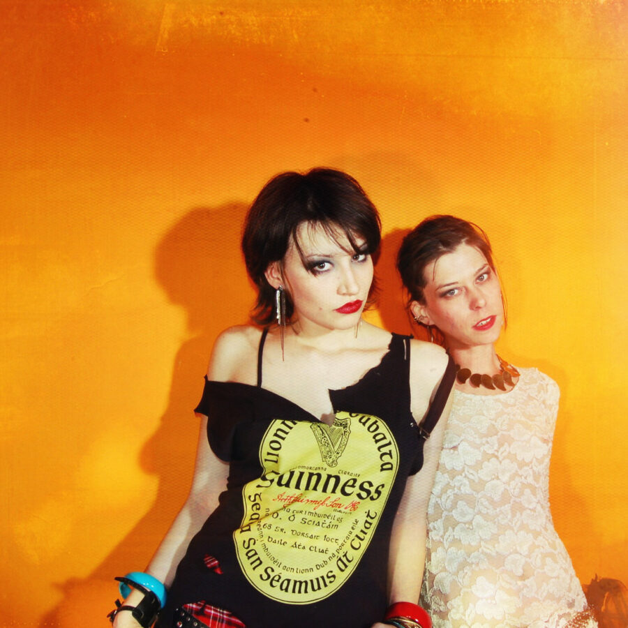 Models in front of a orange wall with red lipstick and white lace.