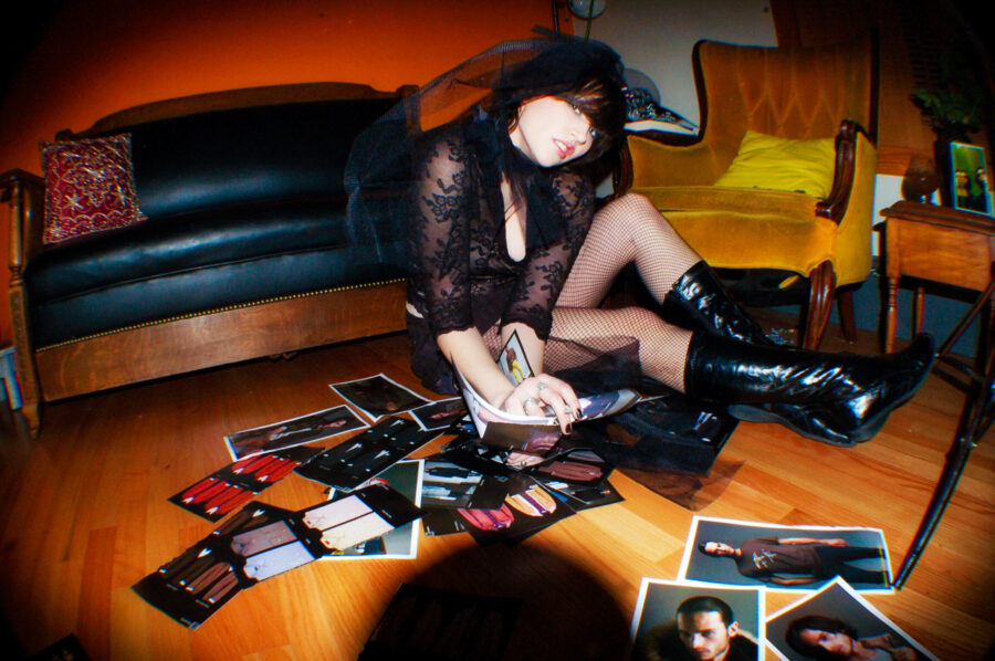 Model in black lace on a floor with fashion photos on the hardwood floor.