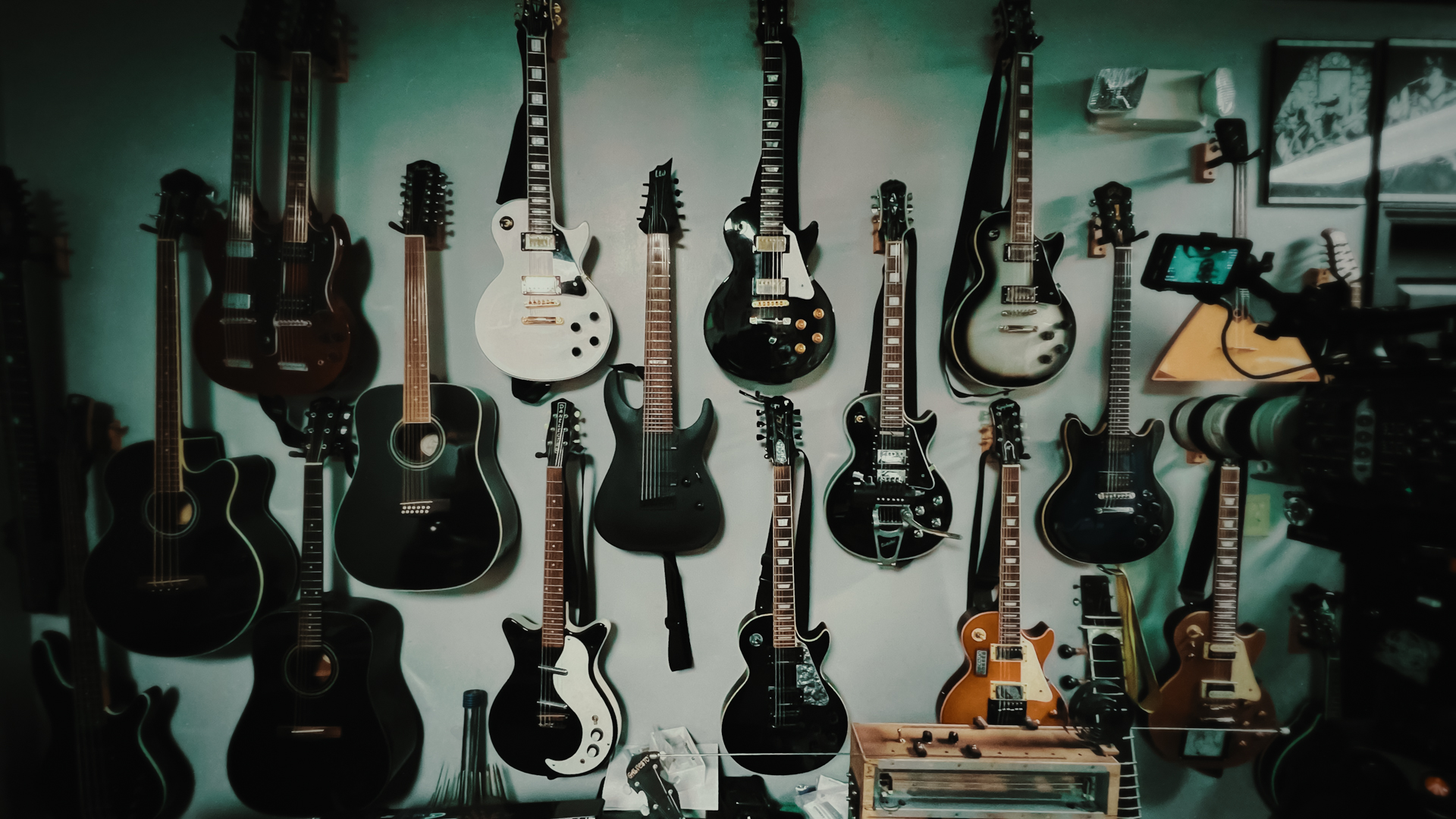 guitars line a green wall in a behind the scenes photo