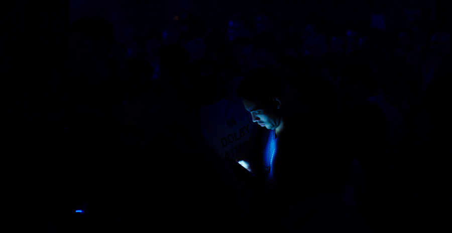 man looks at his phone in a dark club surrounded by blackness