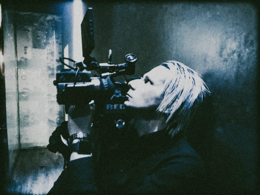 Camera Operator backstage with blonde hair shooting on RED Dragon.