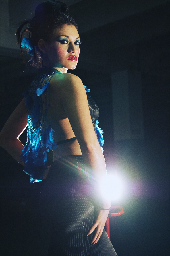 model stands in front of flood light in a warehouse dressed in design clothes