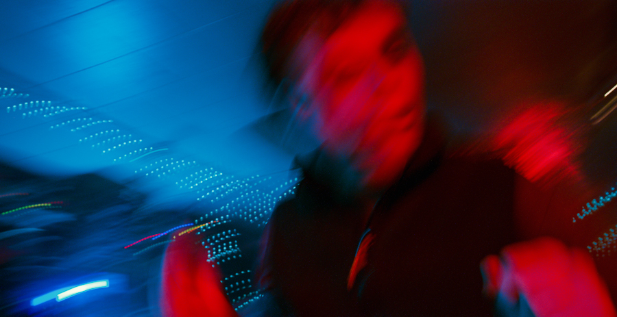 man blurs while running through a neon bar in red and blue light