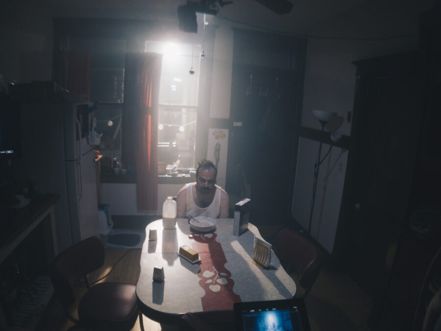 sad man sits in dark harsh lit kitchen w bowl of cereal in the short film 'the Handoff'