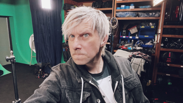 Behind the scenes image of man with white hair looking into camera during a photoshoot.