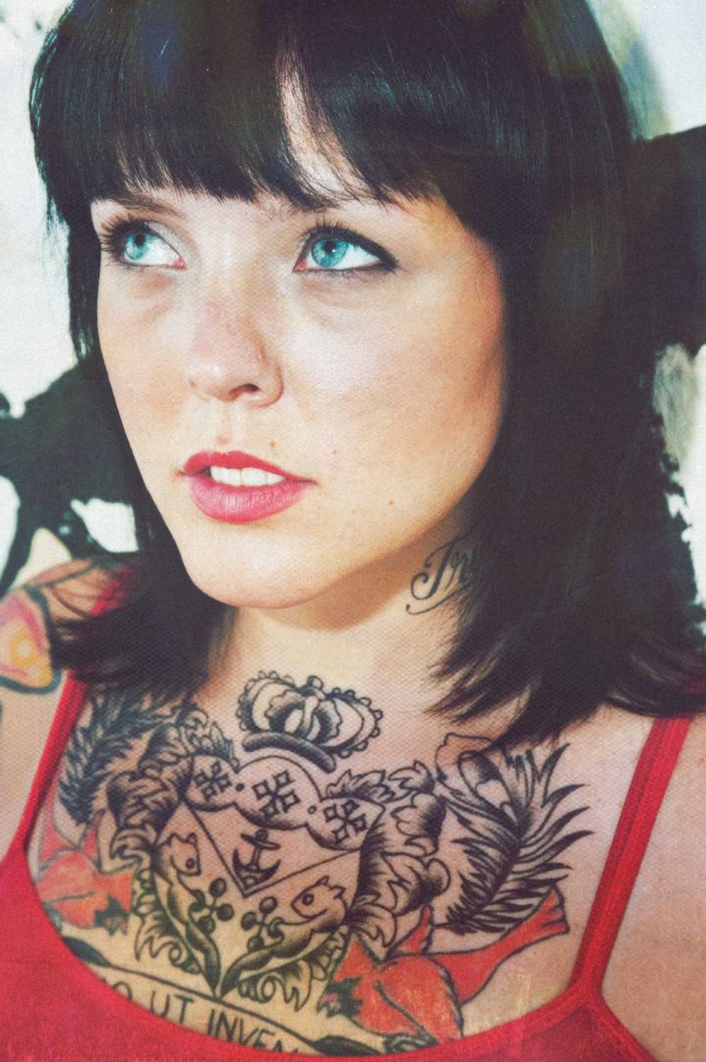 Photo of girl with black hair, tattoos, and red top with damage grain.