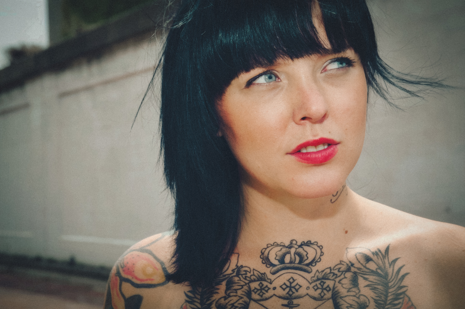 Photo of girl with black hair, tattoos, and black dress next to a overpass highway.