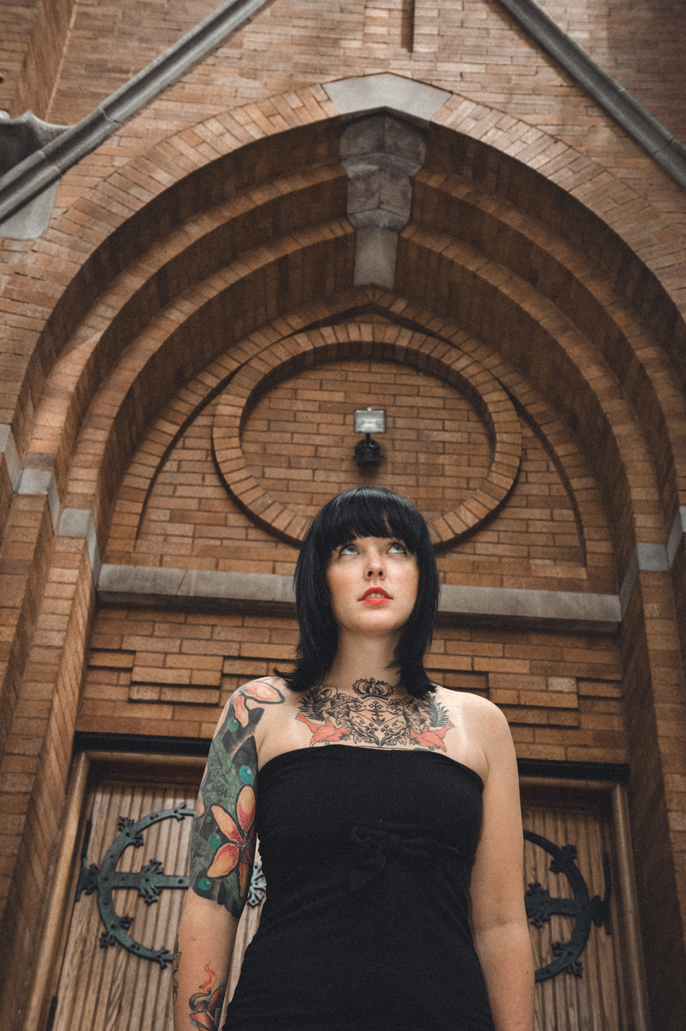 Photo of girl with black hair, tattoos, and black dress in front of a church in downtown Chicago.