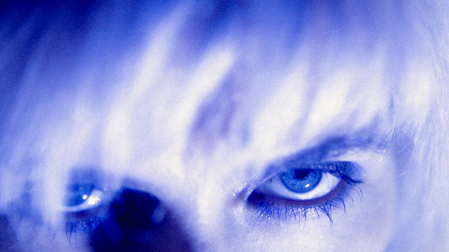 woman mirrored in purple light and blonde hair stares at camera