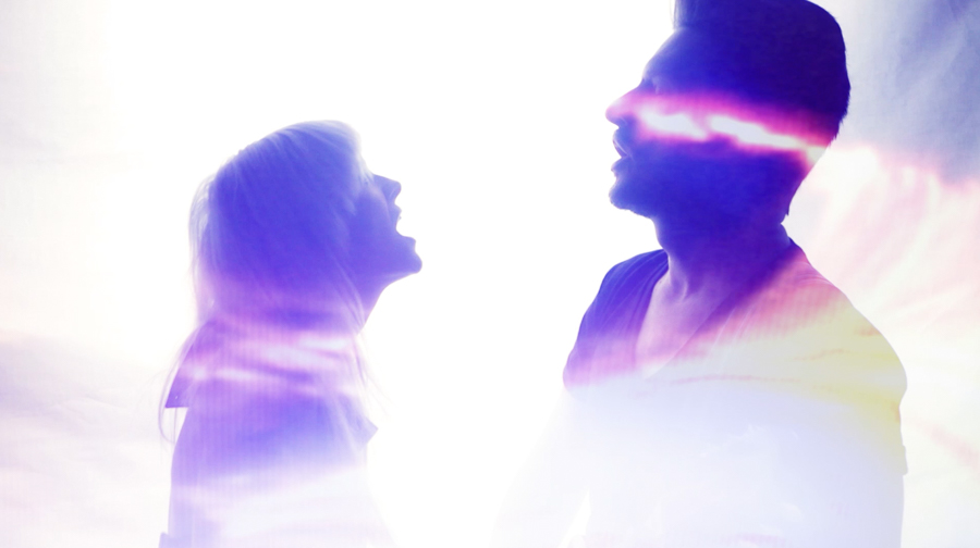 man and woman in purple light streaks sing to each other