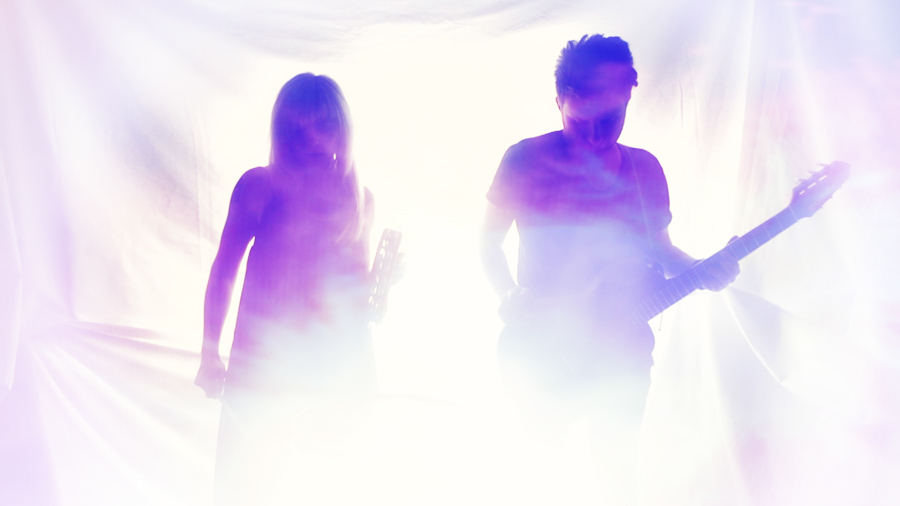 man and woman in purple light streaks lean into camera