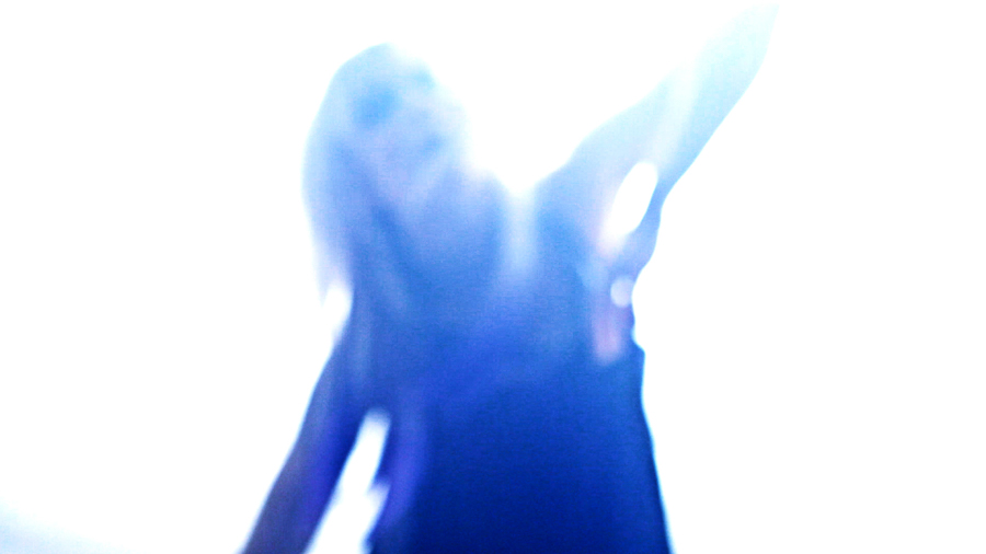 woman in purple light and blonde hair reaches towards sky blurred