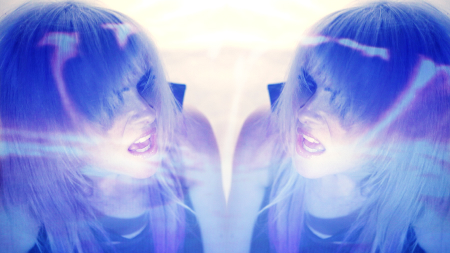 woman mirrored in purple light and blonde hair stares at duplicate of herself
