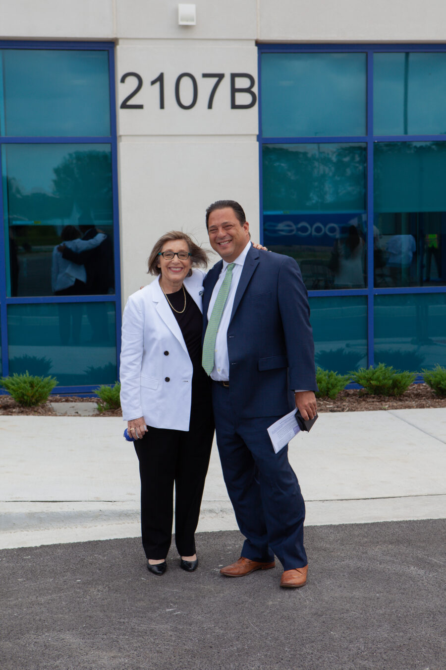 Man and woman pose outside of a building.