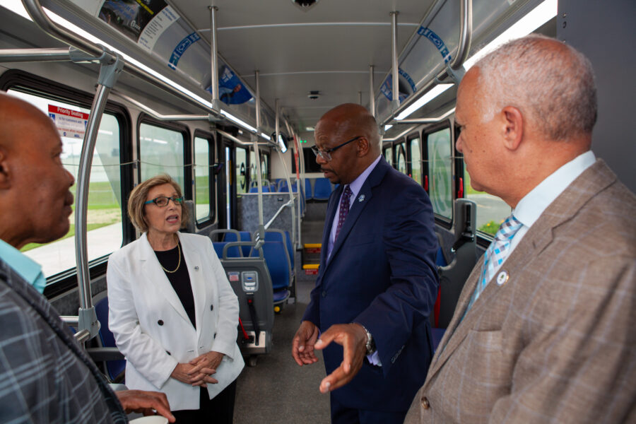 People inside a bus talk and point towards camera.