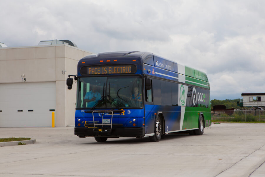 Bus driving in a building parking lot.