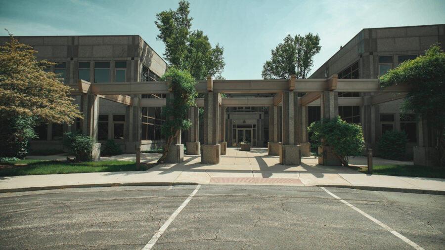 Outside of a building with concrete structures and green bushes and trees.