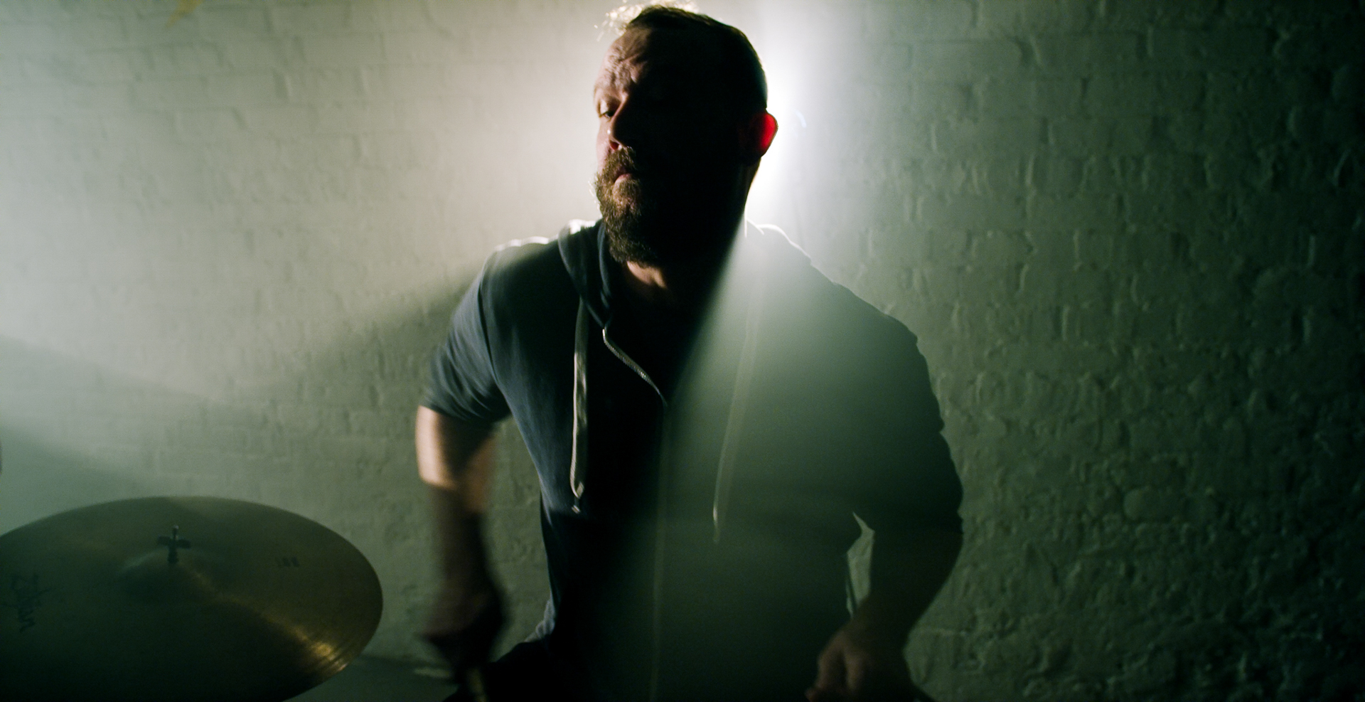 drummer in dark shadows with strong backlight plays drums