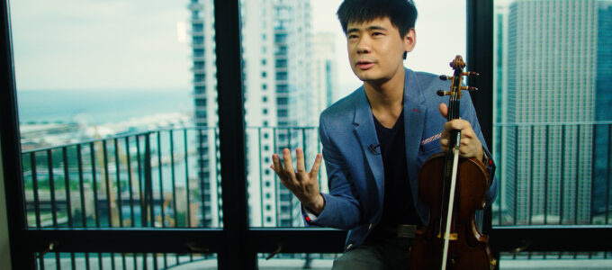 Violinist Angelo Xiang talks during a interview with the chicago skyline behind him