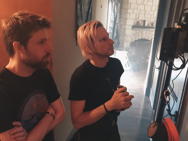 Men in a hallway looking a production monitors during the filming of the short 'Tower Town'.