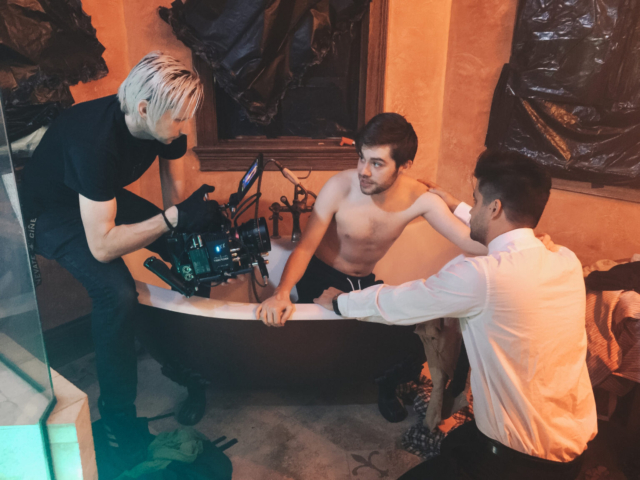 Behind the scenes production of Cinematographer filming man in a bathtub with a RED camera during 'Tower Town'.