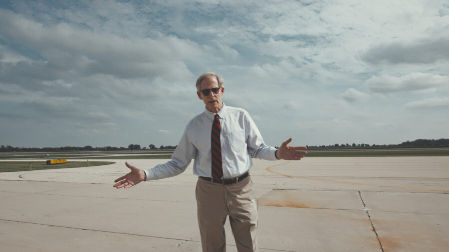 Man standing outside on a airplane runway on a sunny day.