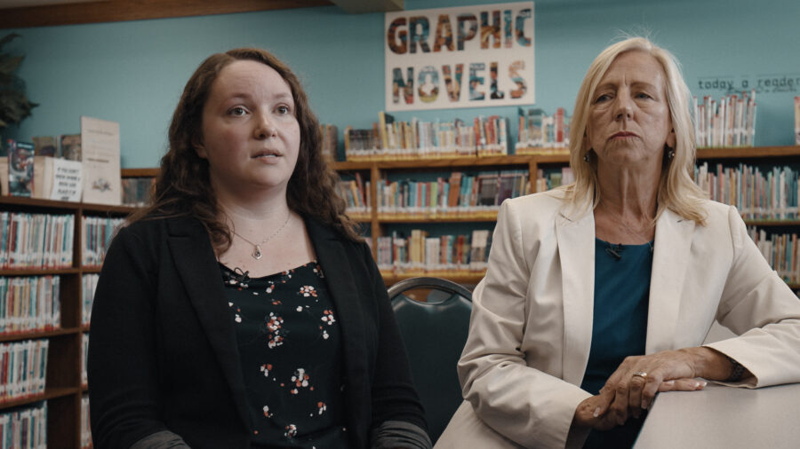 Two women talking during a interview inside a library.