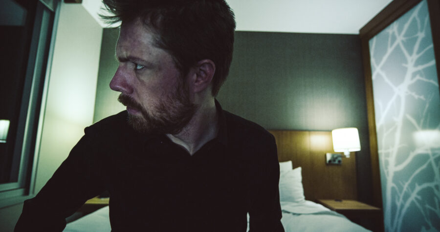 a man, robert felker, sits on the edge of a hotel room bed in a short film by jason kraynek shot on red epic cameras