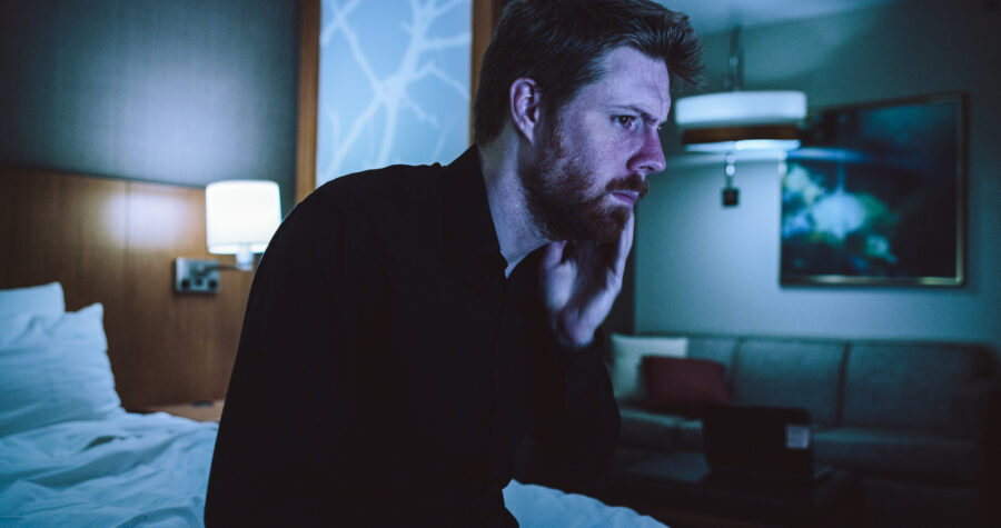 a man, robert felker, holds his jaw on the edge of a hotel room in a short film by jason kraynek shot on red epic cameras