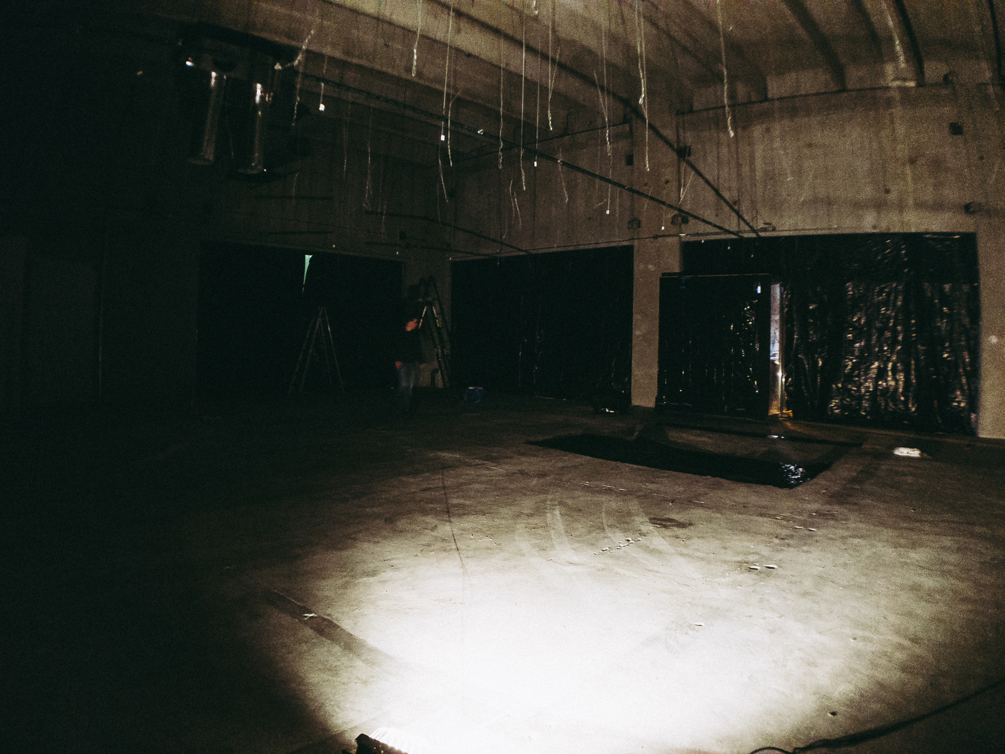 Empty warehouse room with flood lights and garbage bags on windows.