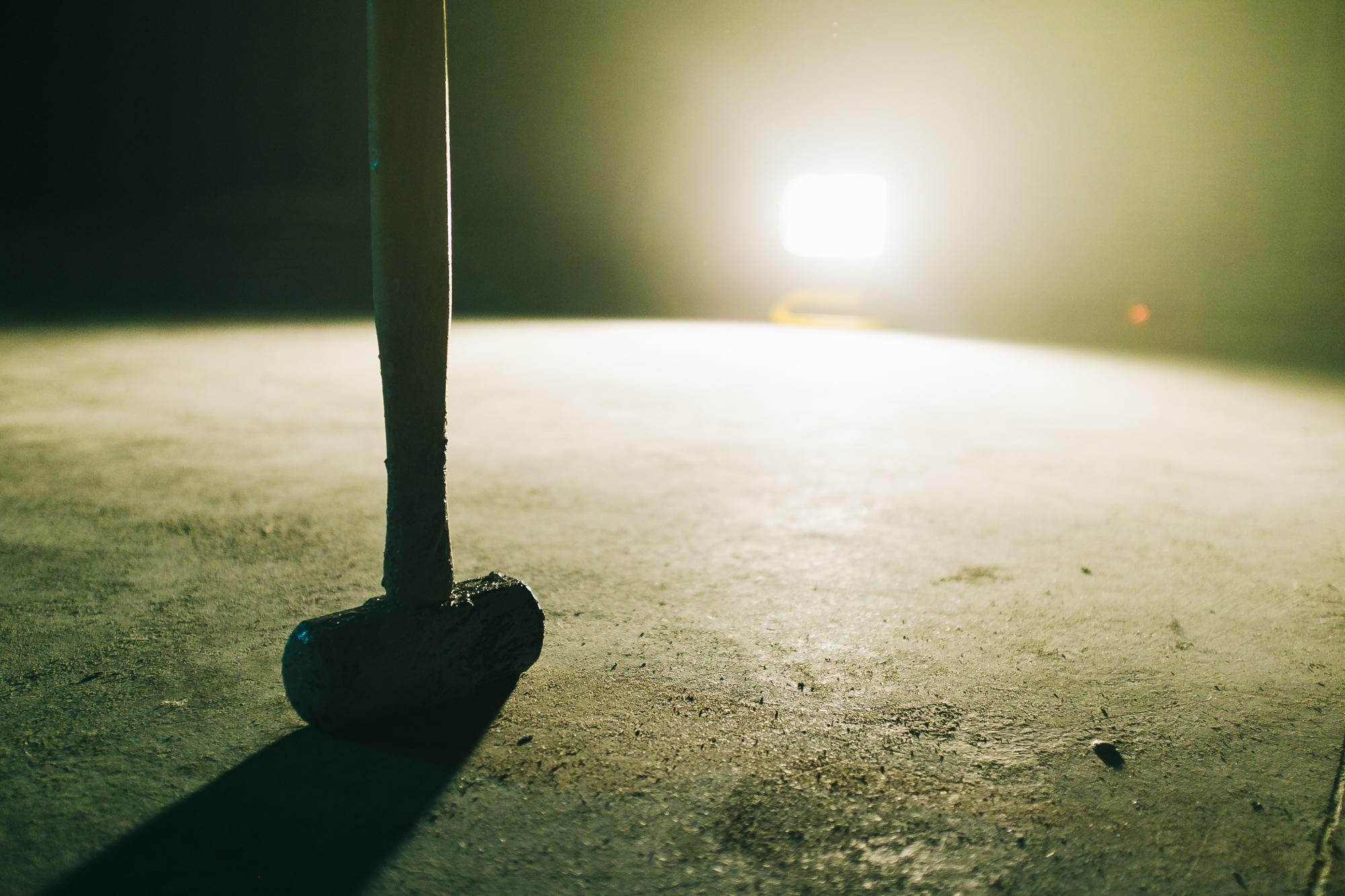Single sledge hammer on ground yellow light shining into camera.