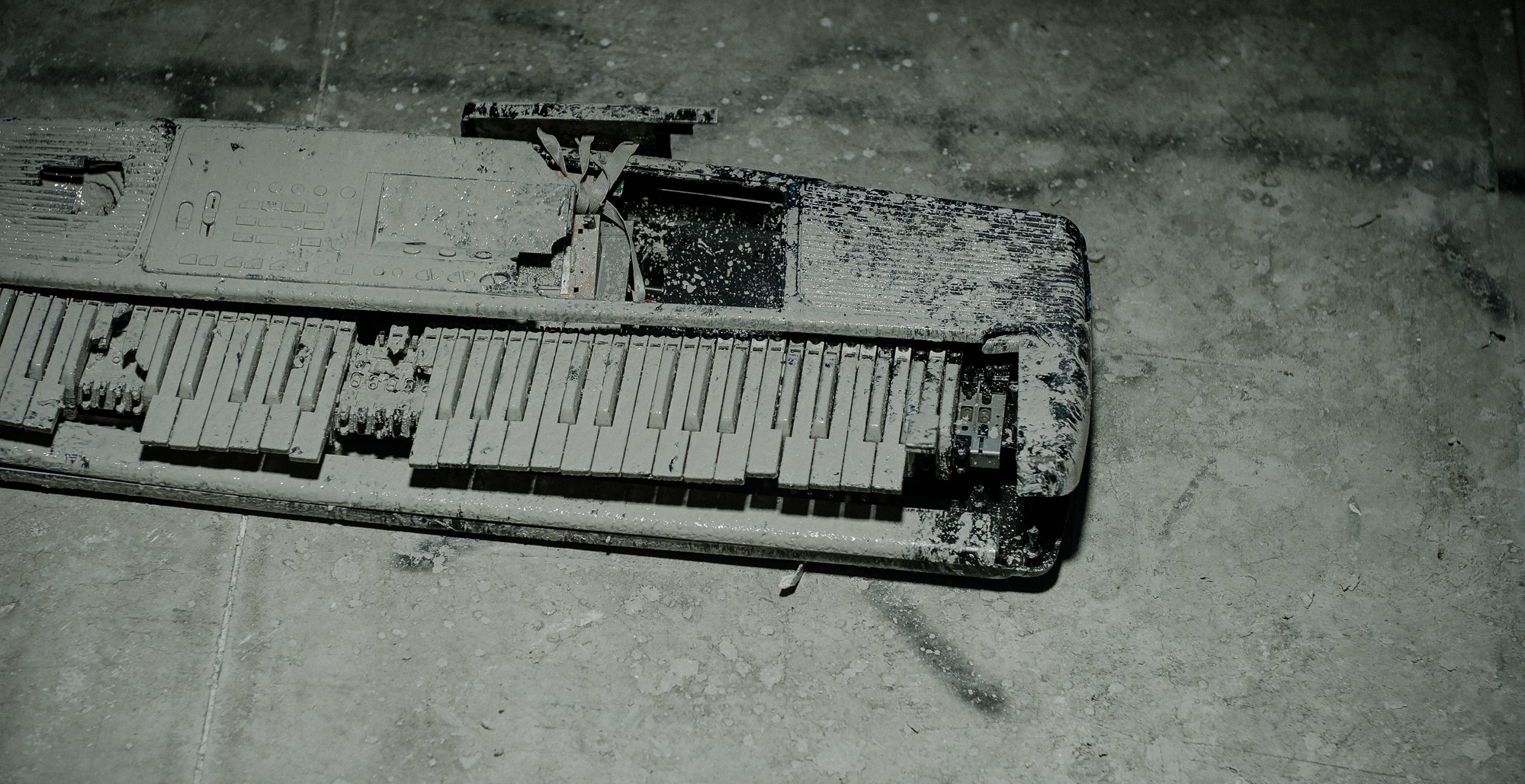 Keyboard covered in white clay broken on floor.